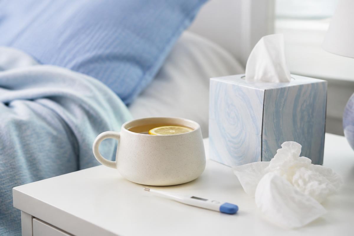 Warm tea with lemon, tissues and a thermometer, representing flu and respiratory infection care
